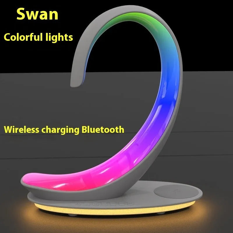 White swan-shaped desktop gadget with wireless charging pad, Bluetooth speaker, and colourful LED atmosphere light.
