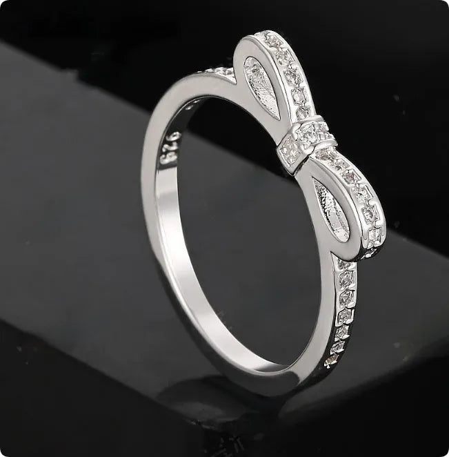 Silver electroplated sterling silver ring with a wide bow design set with clear zircon crystals.