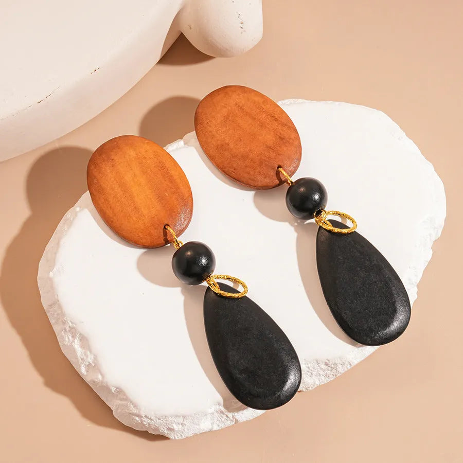 Wooden drop earrings with oval ellipse shape and silver needle accents in brown black colour