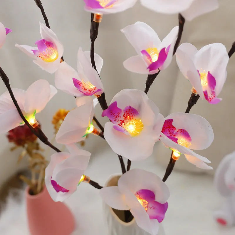 Pink Phalaenopsis-shaped LED decorative light with a bendable 65cm fabric branch on a wooden table.