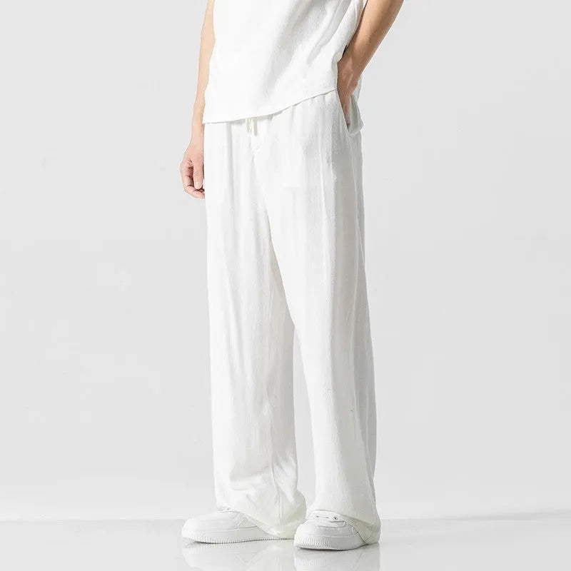 Man wearing beige bamboo fibre drawstring waist trousers with a cropped, straight leg.