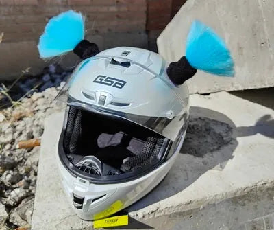 Pair of black helmet braid accessories with 5cm diameter balls next to a non-marking adhesive strip on a table.