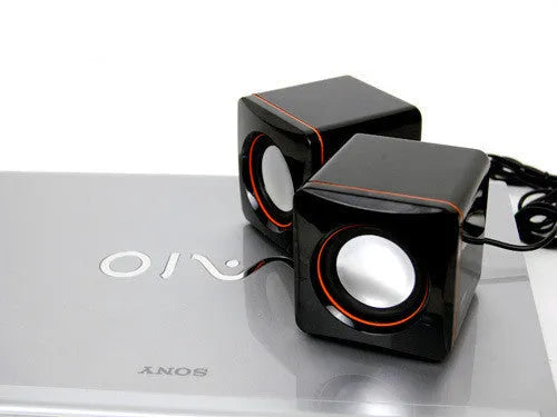 Small square black USB-powered 2.0 desktop computer speaker on a desk.