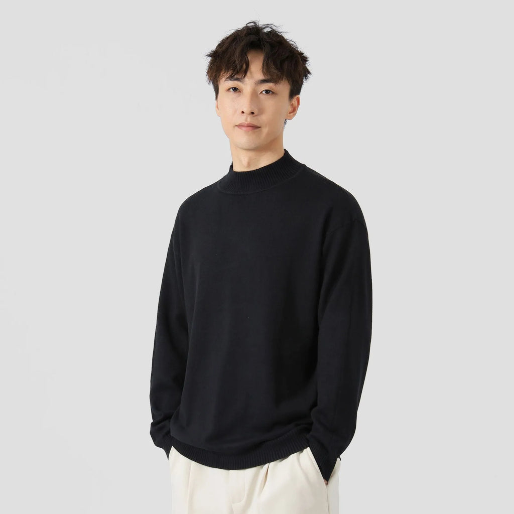 Man wearing a loose-fit long-sleeve solid colour sweater in a casual setting.