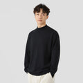 Man wearing a loose-fit long-sleeve solid colour sweater in a casual setting.