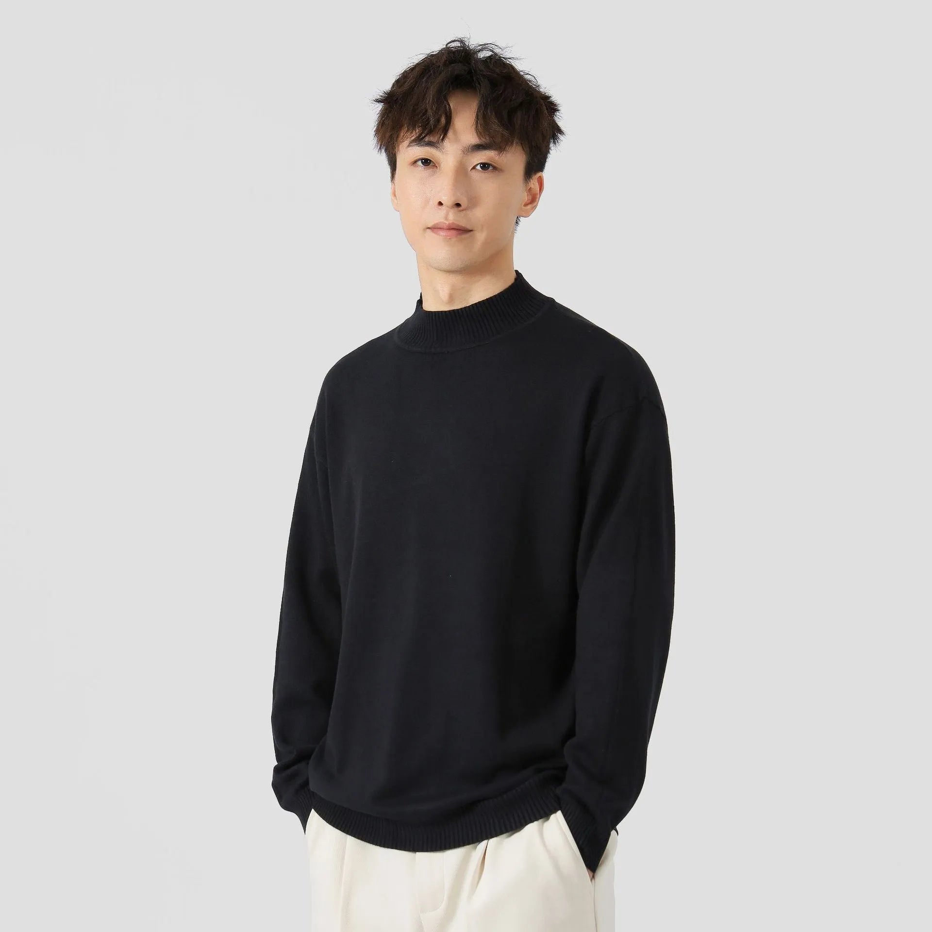 Man wearing a loose-fit long-sleeve solid colour sweater in a casual setting.