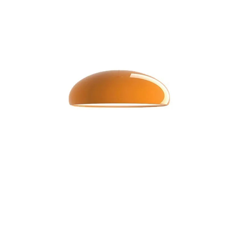Orange iron Danish-style pendant lamp with adjustable cable above a restaurant table.