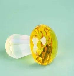 Colourful mushroom-shaped crystal decoration in geometric style on a surface, showing light green hue.