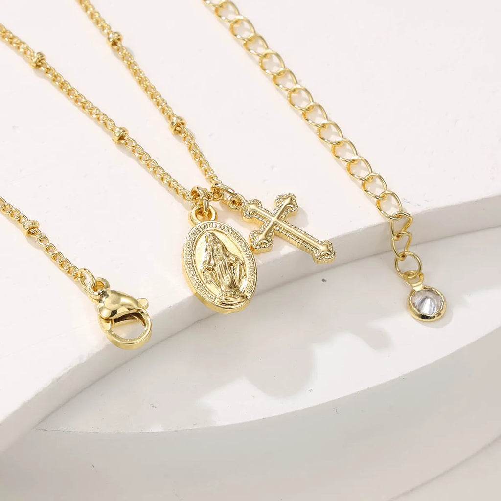 Geometric Virgin Mary cross pendant on a gold chain, showing simple design and 18K gold plating over copper.