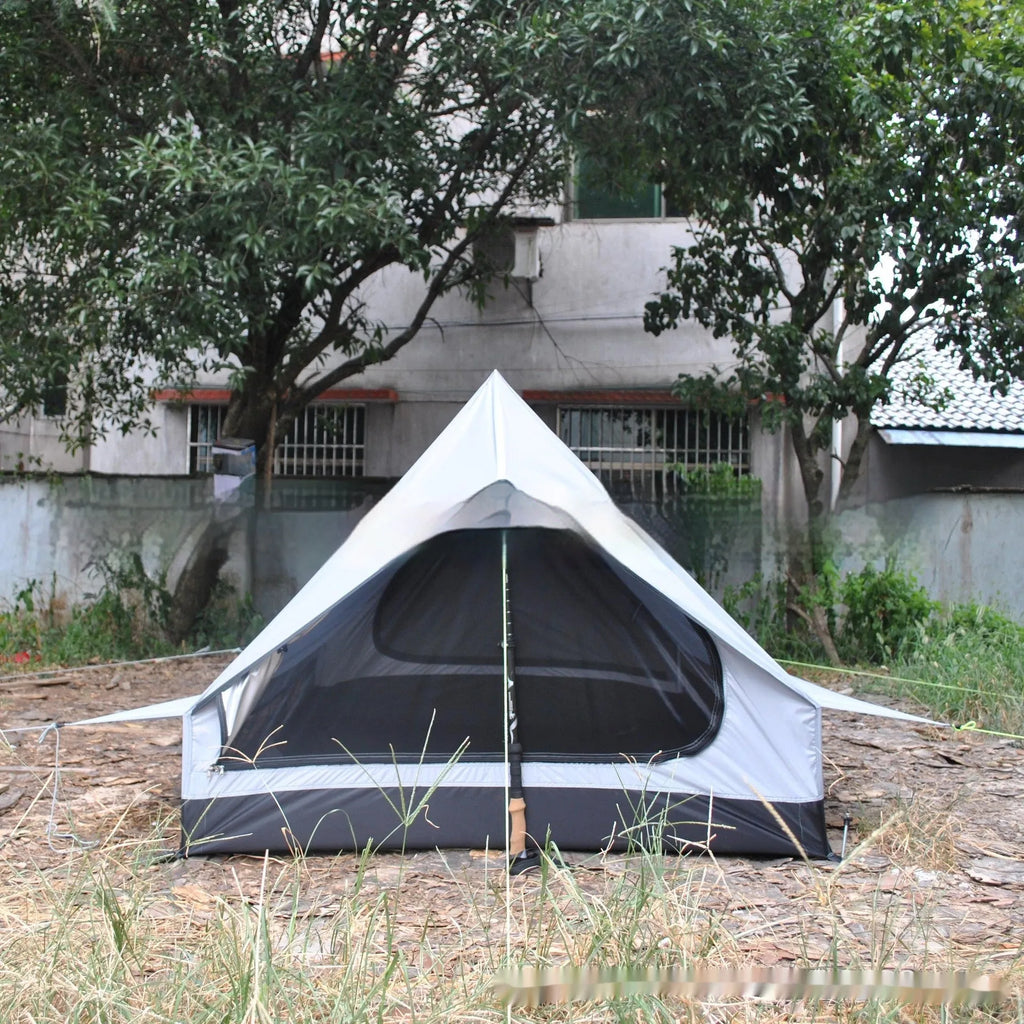 Brown A-Line pole-free cabin tent set up in a forest, showing its spacious interior for 2-3 people.
