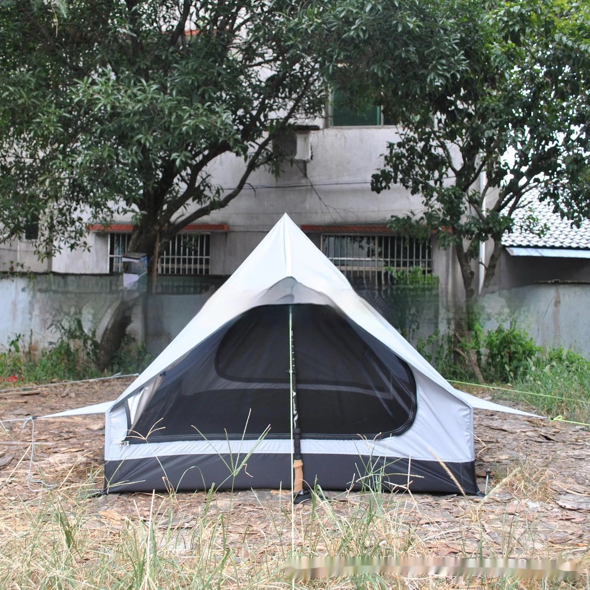 Brown A-Line pole-free cabin tent set up in a forest, showing its spacious interior for 2-3 people.