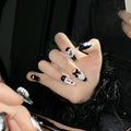 Black pink heart-shaped false nails with hand-painted bow design, Cat's Eye style, in mid-length profile.