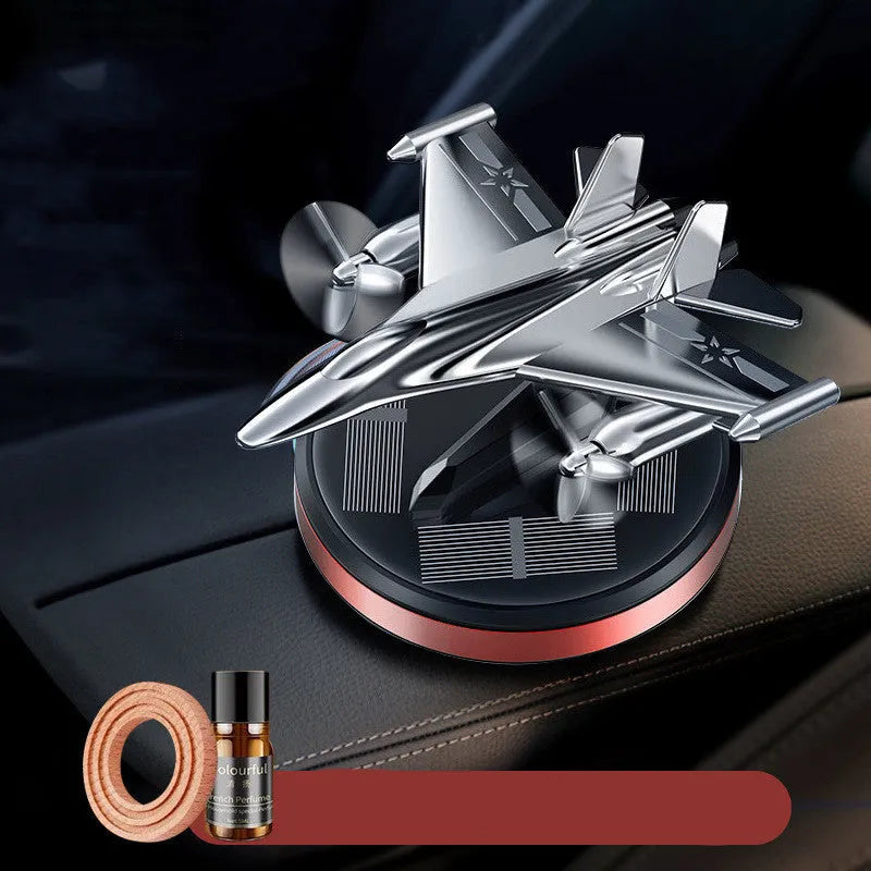 Silver solar-powered rotating fighter aircraft perfume ornament on a surface.