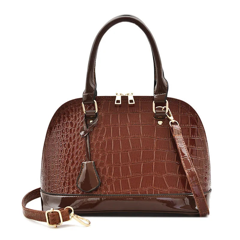 Women's large shiny PU leather crossbody shoulder bag in shell shape, shown in black colour.