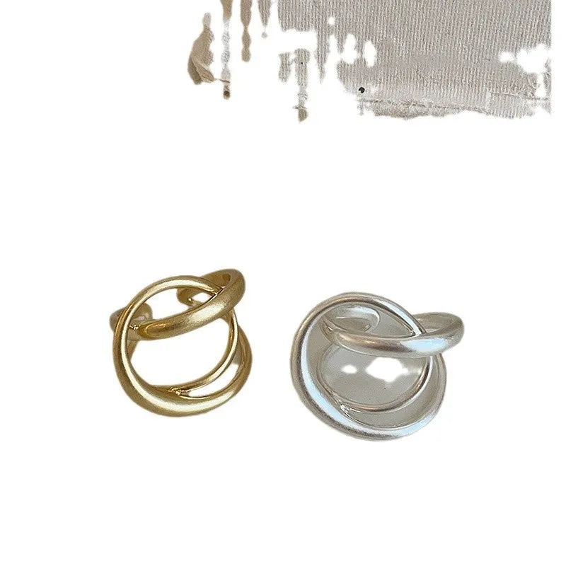 Geometric open ring with interlaced matte metal design in gold or silver plating.