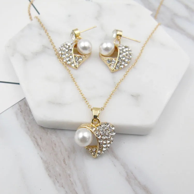 Gold heart pearl jewellery set with alloy necklace and earrings on display