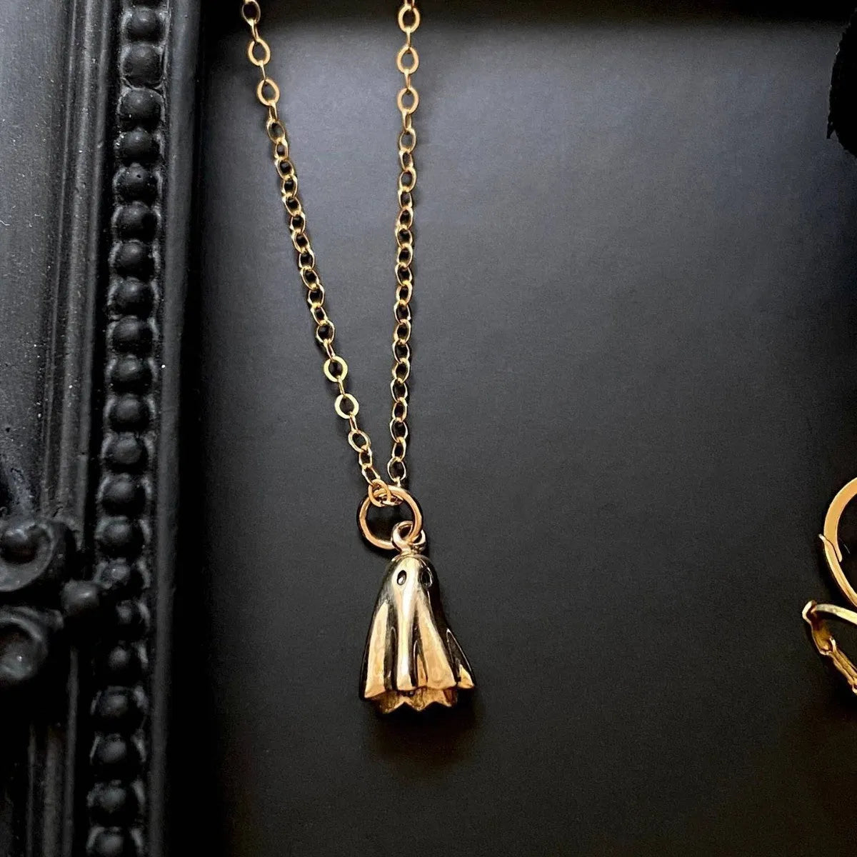 Stainless steel ghost pendant necklace on a twisted chain, showing titanium steel charm.