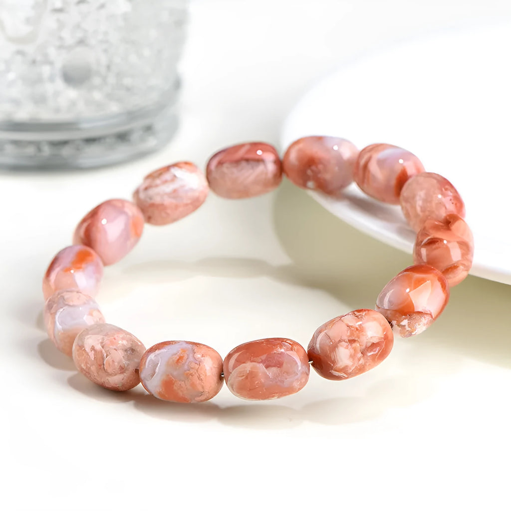 Natural cherry agate barrel bead bracelet with Ruyi symbols on a white background.