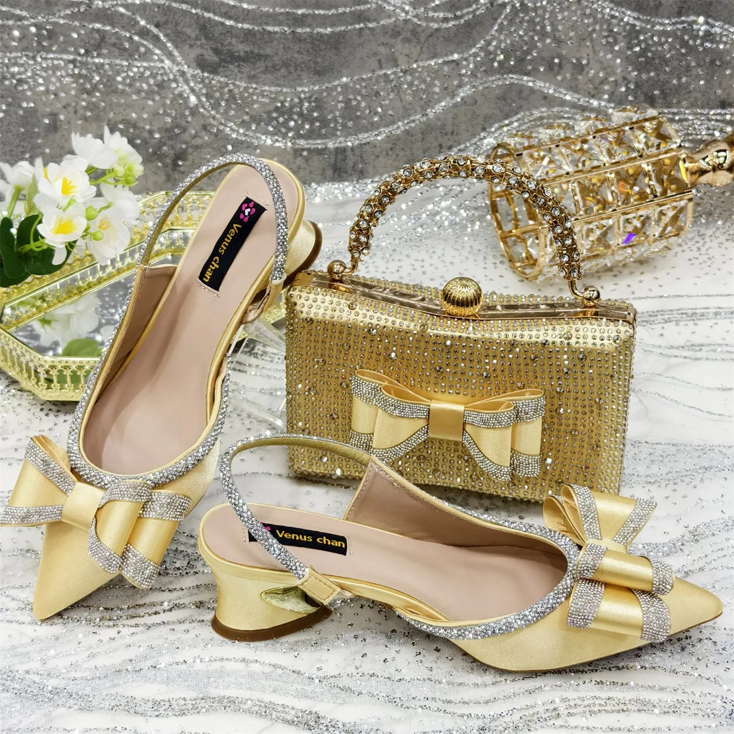 Women's black pointed sandals with mid heel, square rhinestone buckle, elastic band, and matching square bag