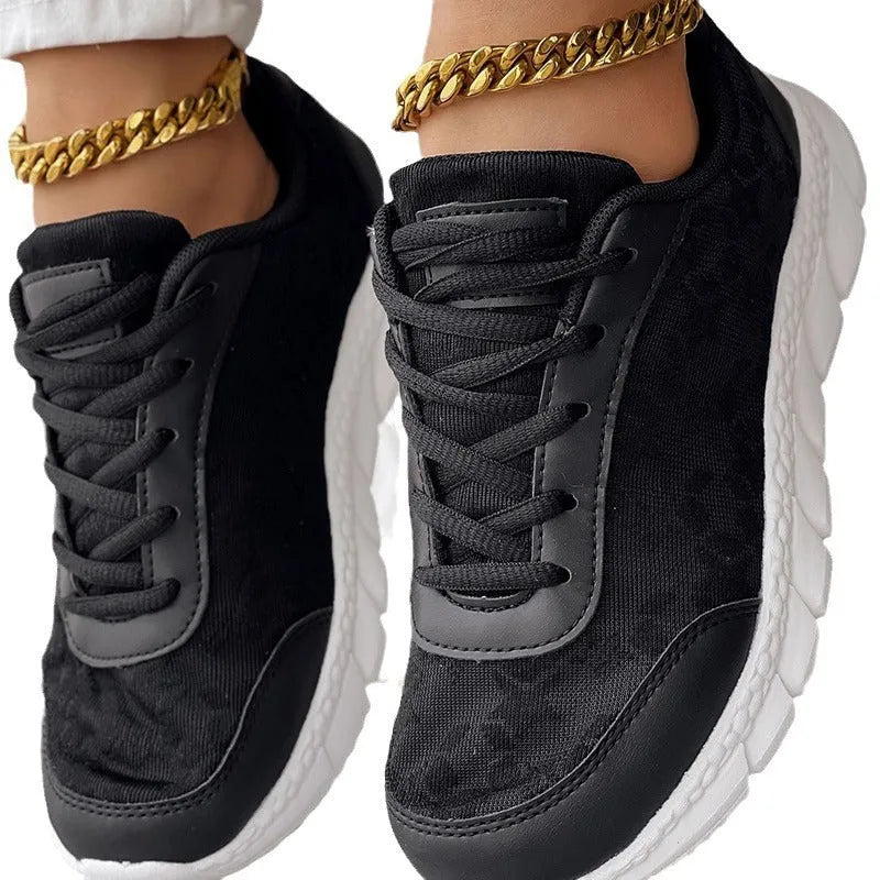 Women's white canvas sports shoes with a flat heel and round toe on a plain background.