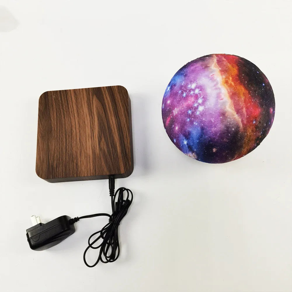 Walnut-coloured magnetic levitation base with floating galaxy-patterned moon lamp illuminated in dark setting