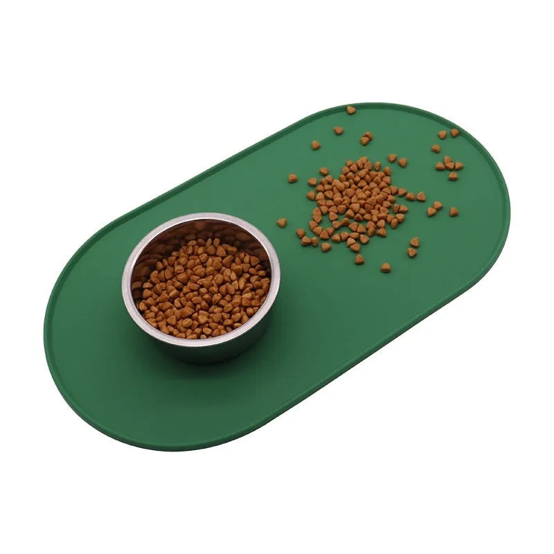 Beige silicone cat feeding mat with raised edges holding a food and water bowl on a wooden floor.