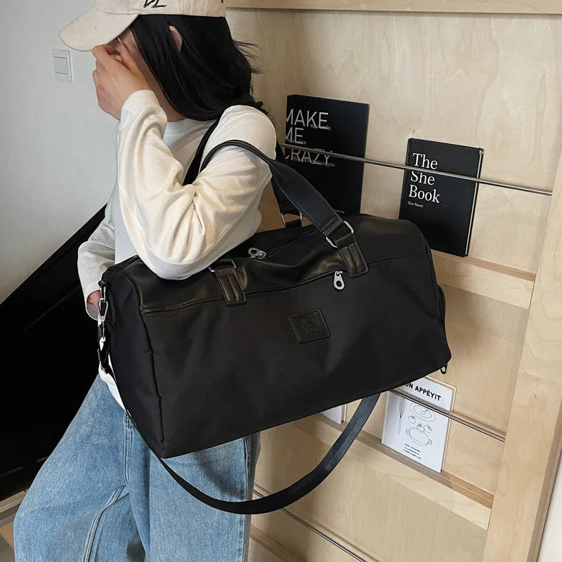 Large black Oxford cloth travel messenger bag with a 36-55 litre capacity shown on a shoulder.