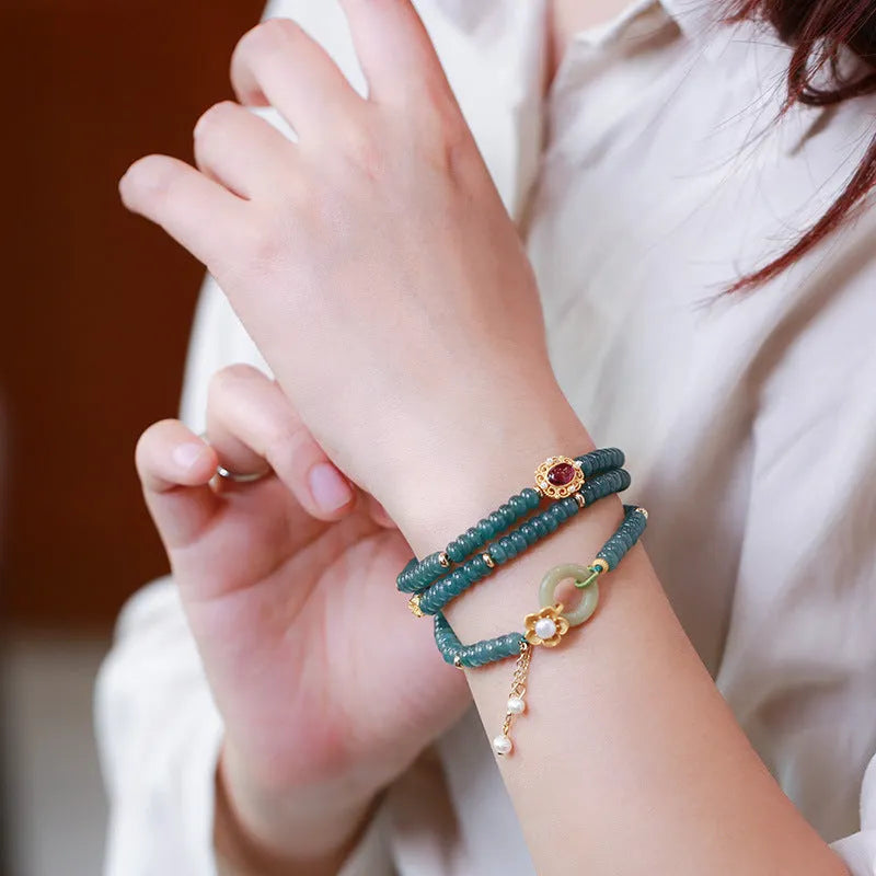 Women's bracelet with small blue water jade abacus beads, tourmaline rings, and pearls on a wrist