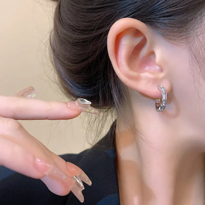 Silver-toned copper geometric eardrop earring with small zircon accent on white background