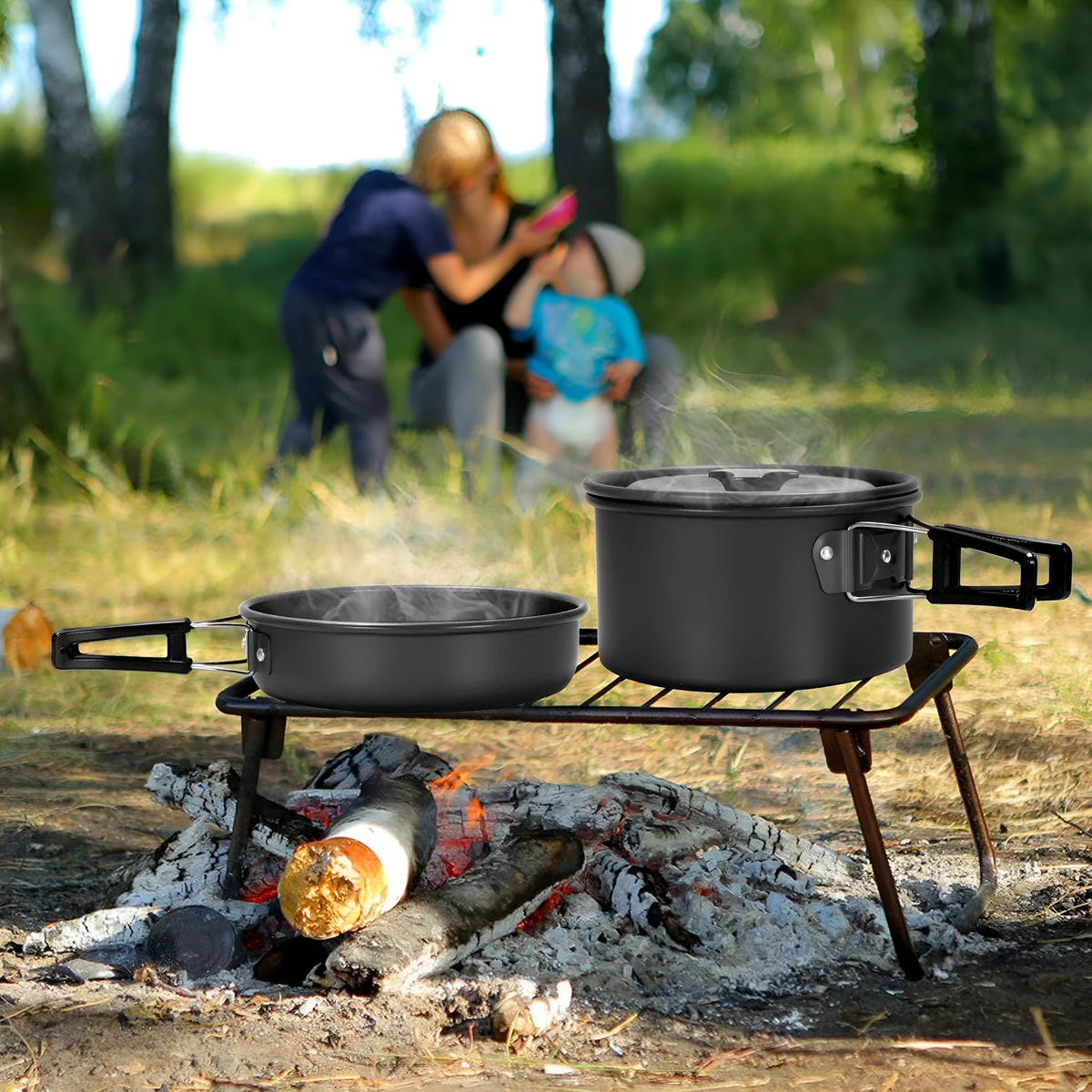 Camping cooker set with hard aluminium boiling pan, frying pan, teapot, stainless steel cutlery, cups, and plates on outdoor table
