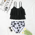 Black high-waisted two-piece swimsuit with a coconut tree print on a model, showing the brief style and double-layer construction.