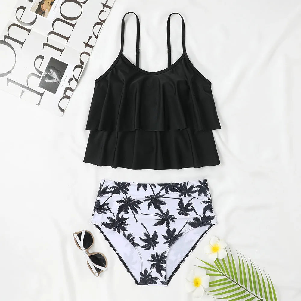 Black high-waisted two-piece swimsuit with a coconut tree print on a model, showing the brief style and double-layer construction.