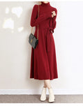 A rose red turtleneck knit dress with long sleeves, a loose hem, and an elastic waist on a hanger.