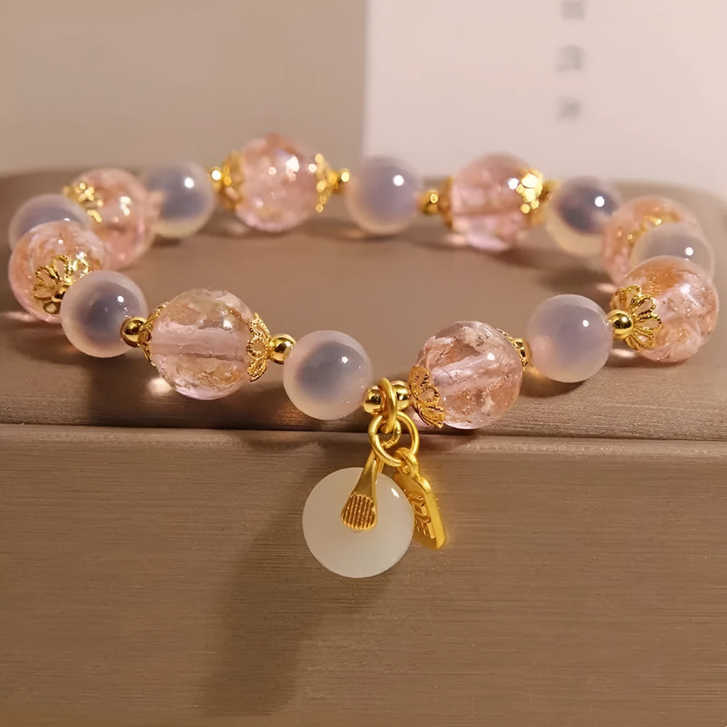 Close-up of a women's pink agate heart bracelet with a luminous glaze and a silver peace buckle clasp.