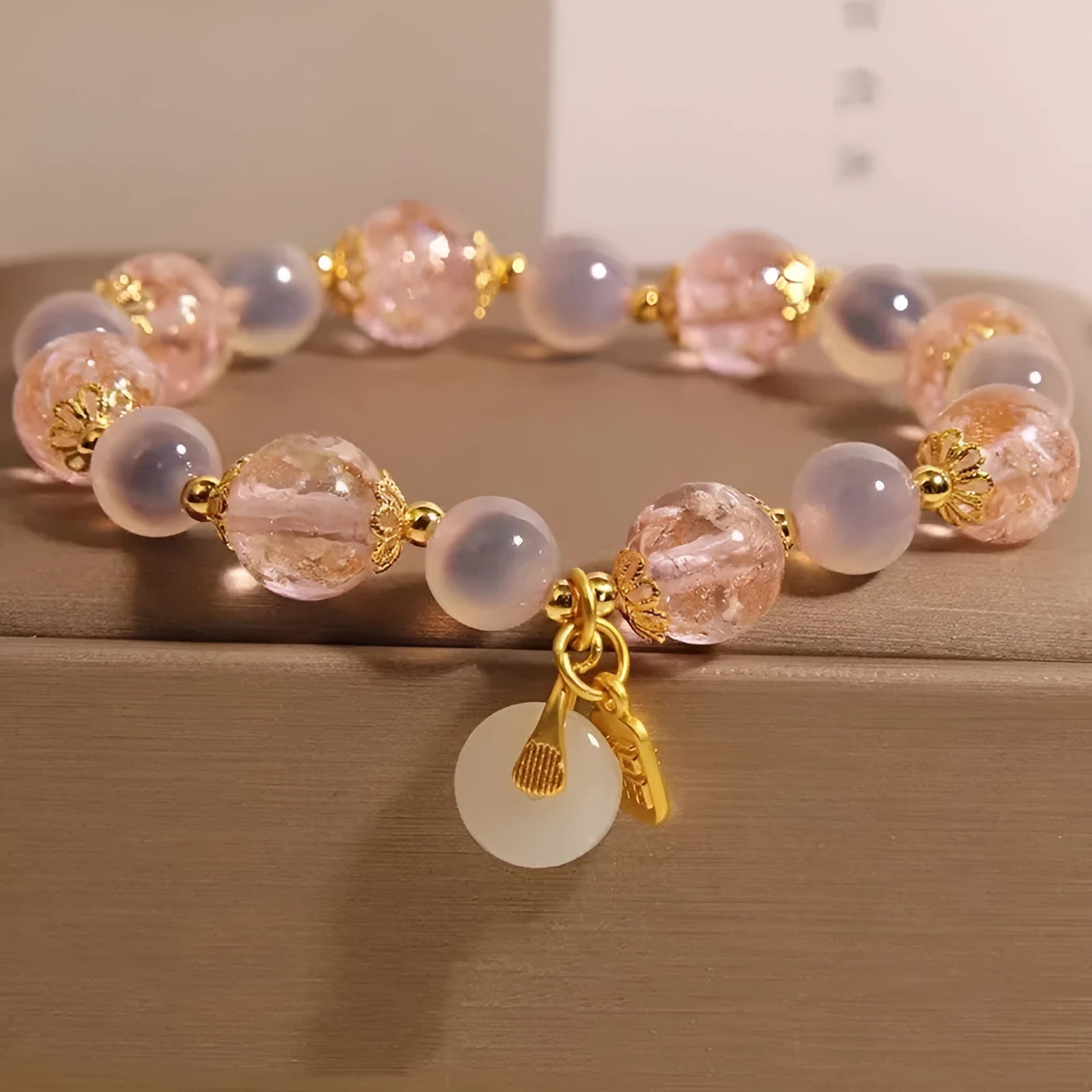 Close-up of a women's pink agate heart bracelet with a luminous glaze and a silver peace buckle clasp.