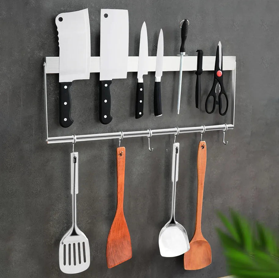 Stainless steel wall-mounted magnetic knife storage rack on a kitchen wall.