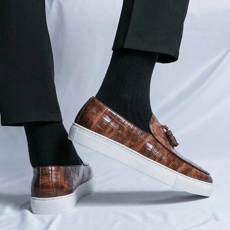 Men's black slip-on sneakers with a decorative tassel and round toe on a rubber sole.