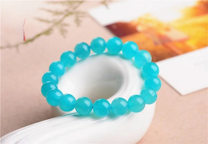 A selection of loose, polished ice-blue Amazonite beads in various sizes next to a finished crystal bracelet.