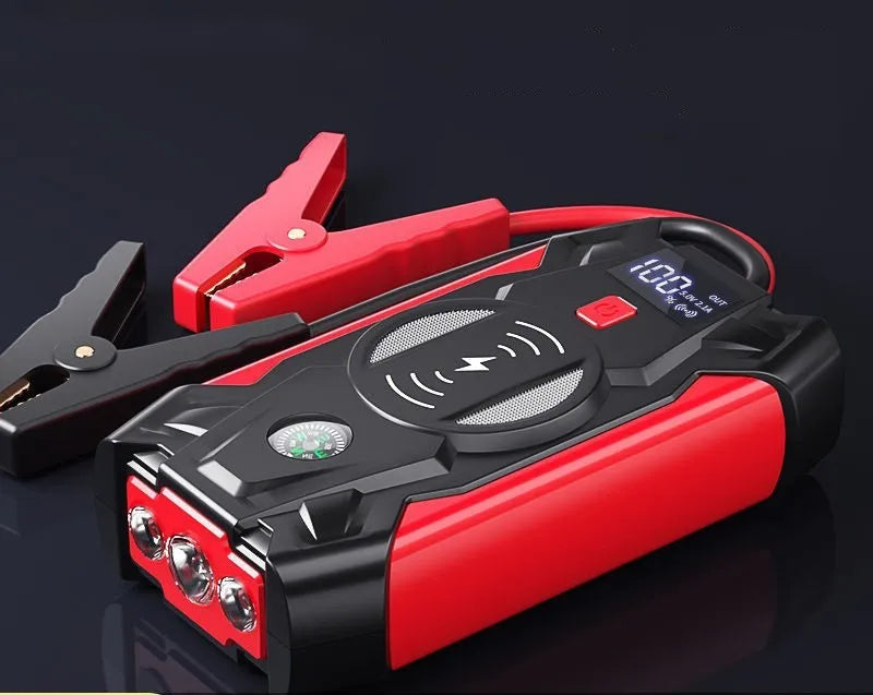 Red car emergency jump starter power pack with digital display and strong jumper clamps.