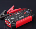 Red car emergency jump starter power pack with digital display and strong jumper clamps.