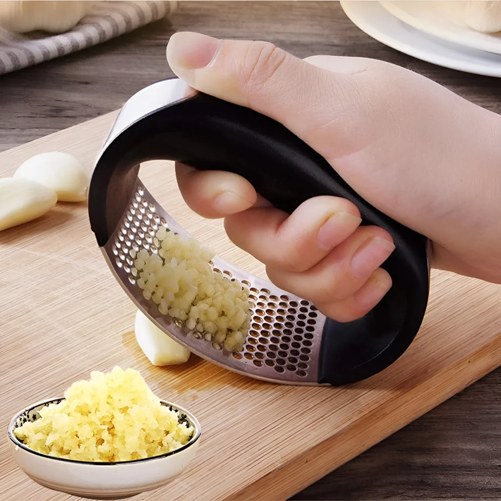 Stainless steel garlic press with ergonomic handle in assorted colours on a kitchen counter.