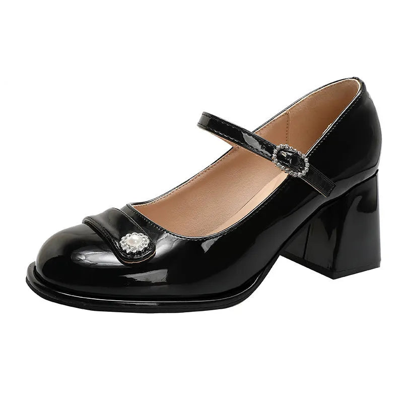 Women's black patent leather wide fit court shoes with a round toe and chunky buckle fastening heel.