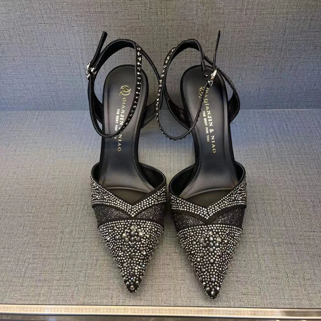 Women's black hollow high heel shoe with red sole, stiletto heel, and pointed toe on a plain background.