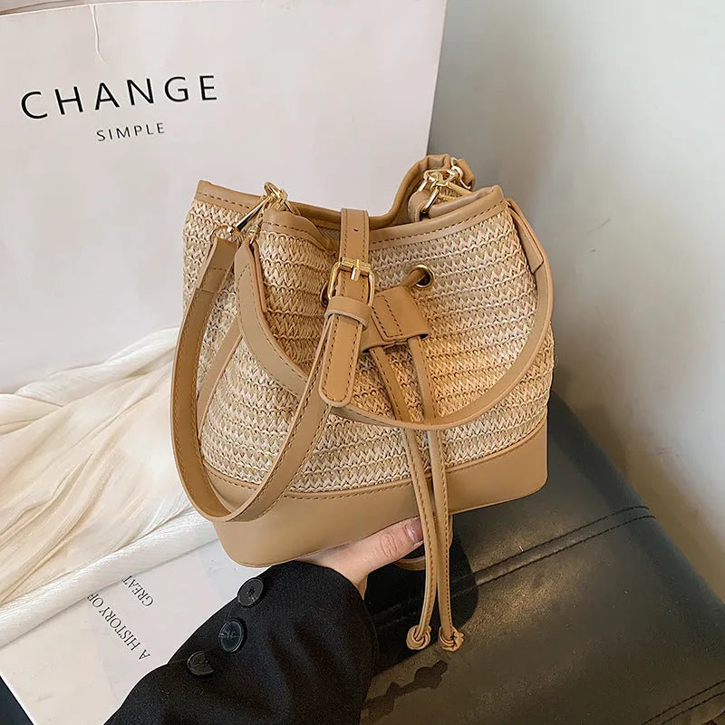 Woven straw women's crossbody bucket bag in brown colour showing horizontal square shape
