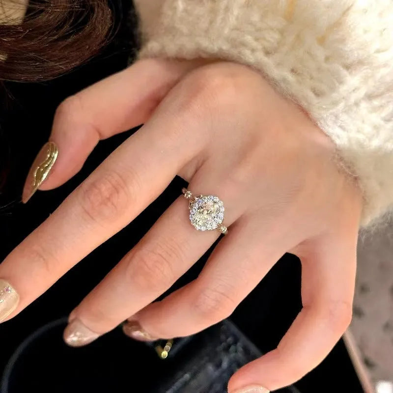 Silver geometric elliptical ring with large diamond on model's index finger, showcasing adjustable opening.