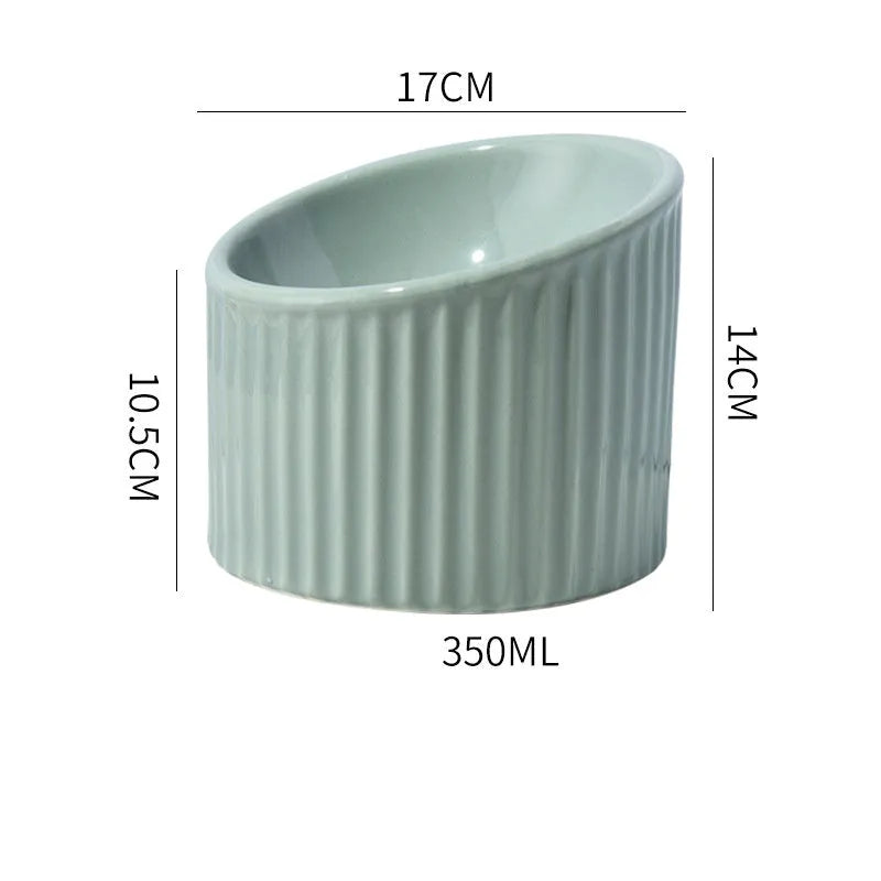 A ceramic elevated cat bowl with a tilted, round design shown in green, positioned on a floor.