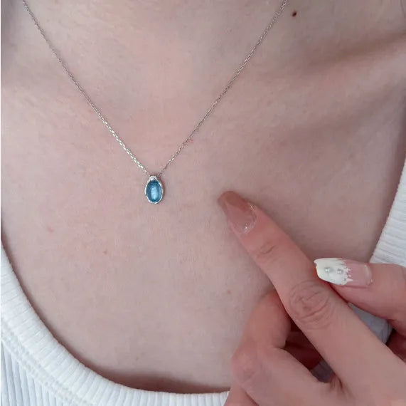 Close-up of a navy blue geometric water drop pendant on an adjustable silver-tone chain