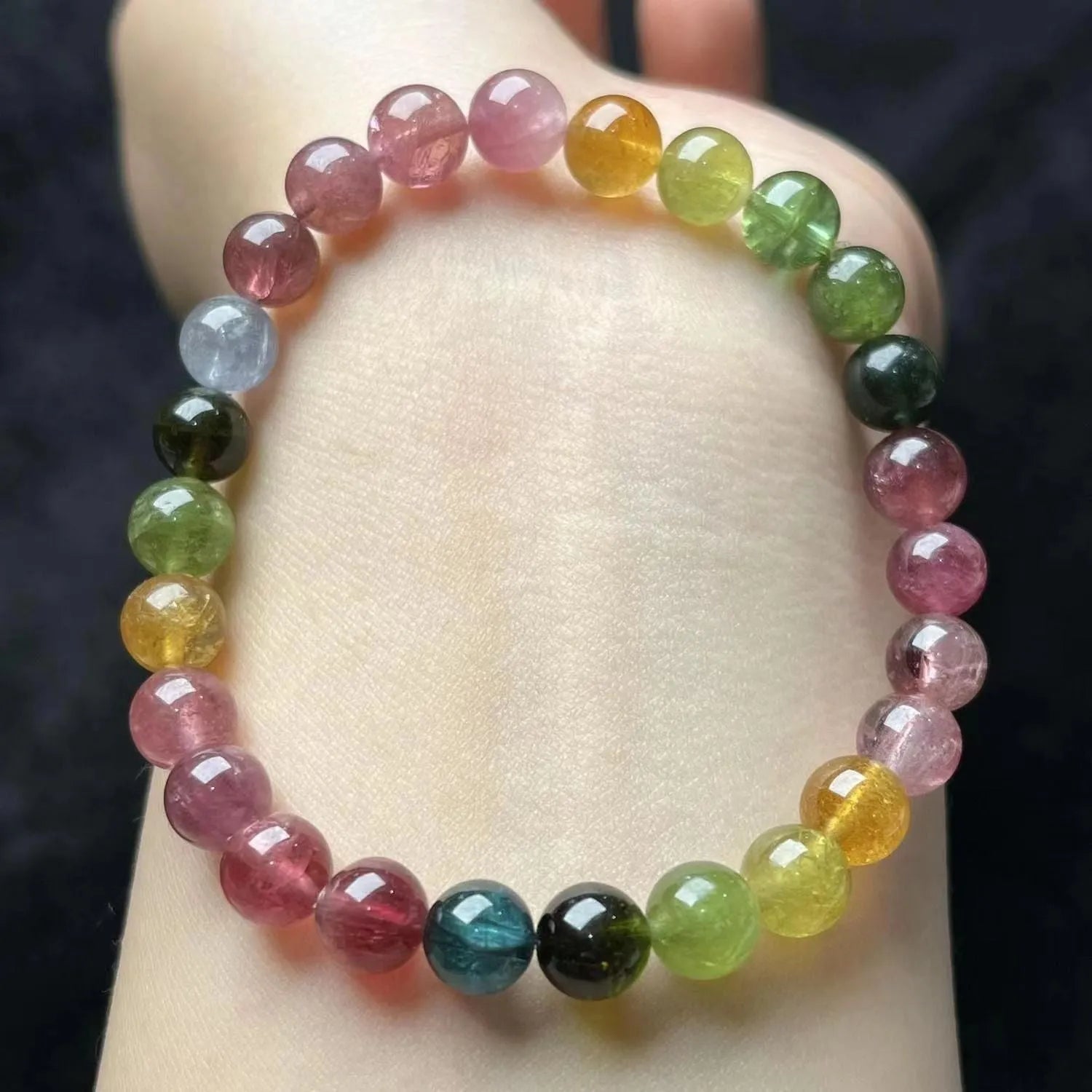 Natural colour tourmaline bracelet with four-leaf clover pearl pendant, geometric drop shape on woman's wrist.