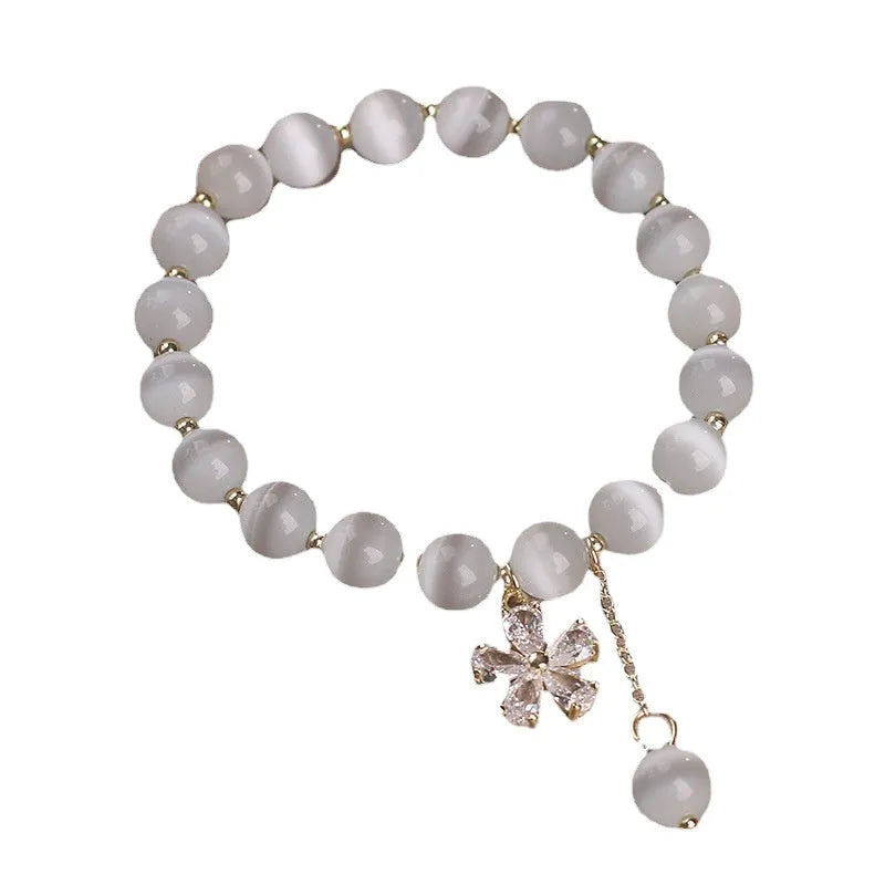 White cats eye crystal bracelet with flower charms, tassels and safety buckle closure
