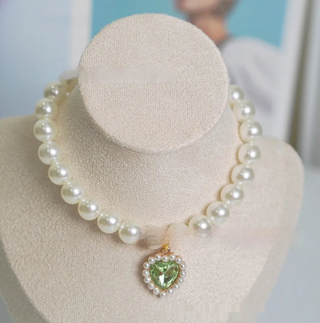 Pearl necklace cat collar with heart-shaped gem charm in various colours on a white background.